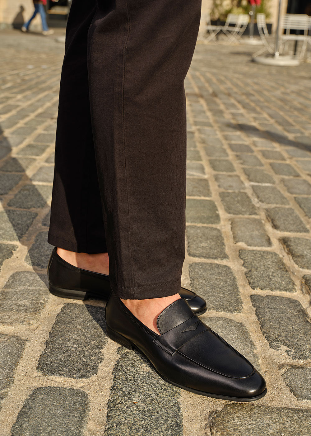 Man in a black pants wearing To Boot's Keats Black Calf Leather Loafer standing on a cobblestone street.